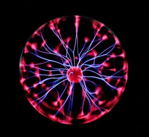 Close-up of a plasma globe with vibrant neon sparks against a dark background.